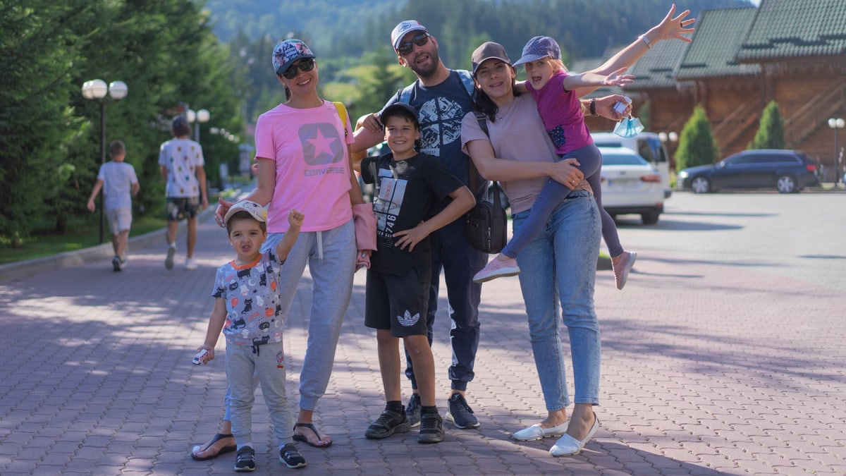 A joyful family of six spending quality time together in a scenic outdoor setting with mountains in the background.